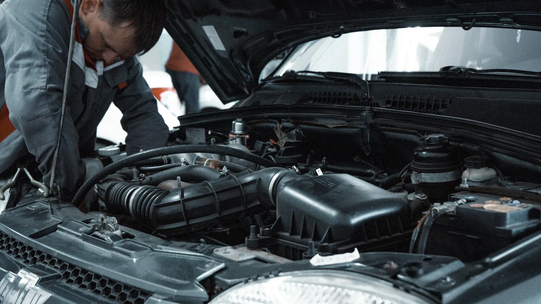 Mecanic care verifică motorul unei mașini cu capota deschisă