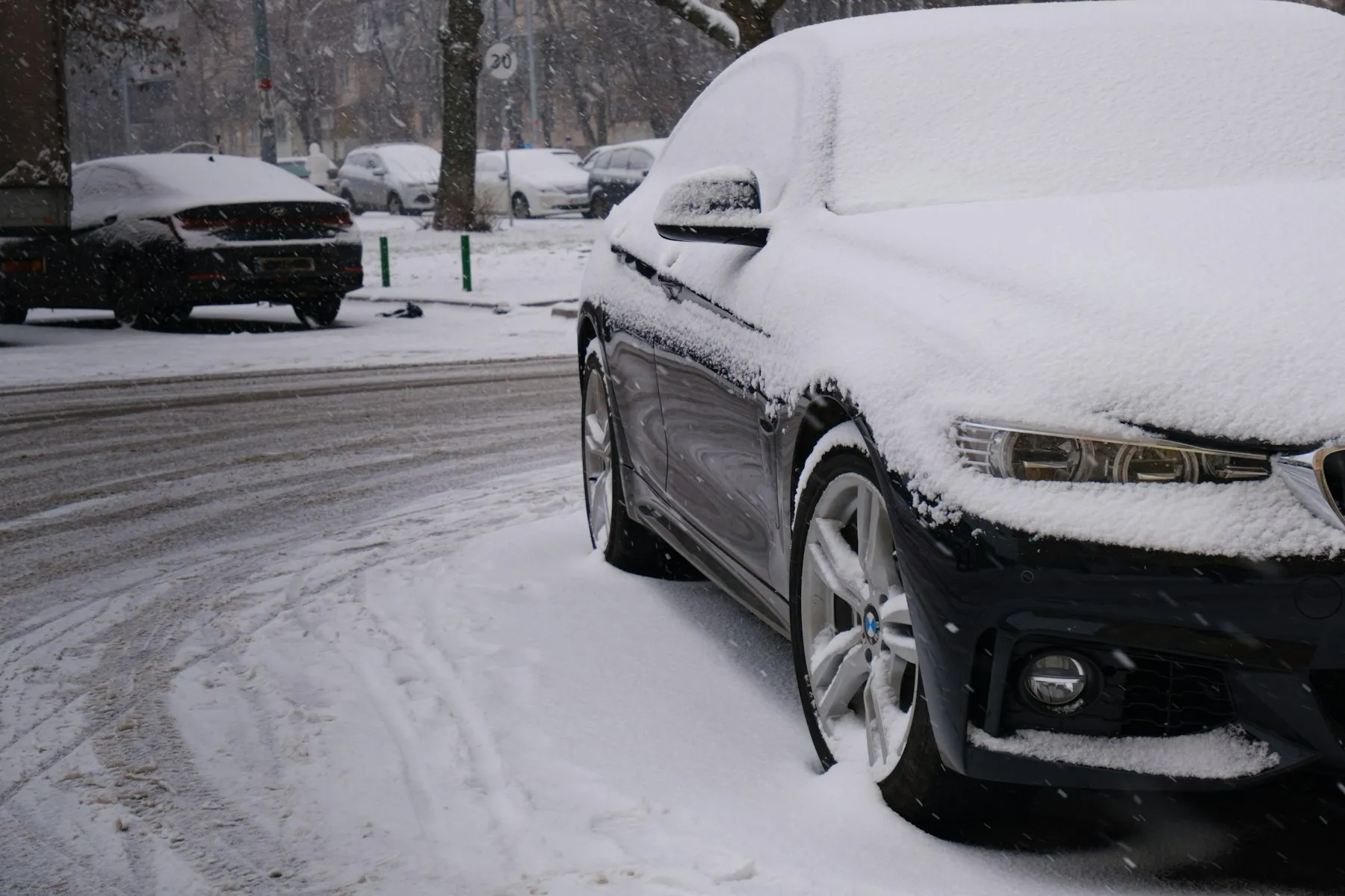 Parkeret bil dækket af sne på en vintergade